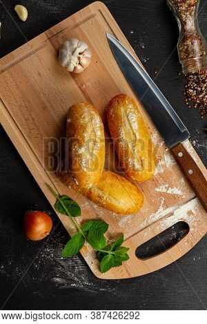 Fresh Wheat White Bread On A Cutting Board With Seasonings Sprinkled With Flour On A Black Wooden Ta