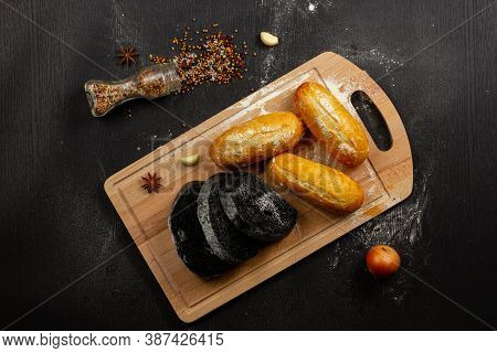 Fresh Black Rye And White Bread On A Cutting Board With Seasonings Sprinkled With Flour On A Black W
