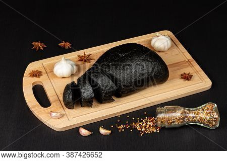 Fresh Black Rye Bread On A Cutting Board With Seasonings Sprinkled With Flour On A Black Wooden Tabl