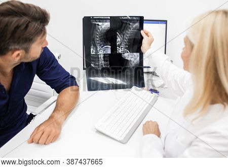 Neurologist Considers And Discusses With Man Patient An X-ray Image Of His Cervical Spine. Diagnosti