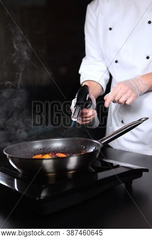 Gas Burner In The Hands Of The Chef. Cooking Flamb Dishes From Berries And Fruits.flaming Of Fruits 