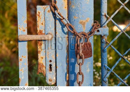 Old rusty gate locked by a padlock and chain