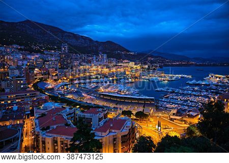 Aerial view of Monaco Monte Carlo harbour and illuminated city skyline in the evening blue hour twilight. Monaco Port night view with luxurious yachts