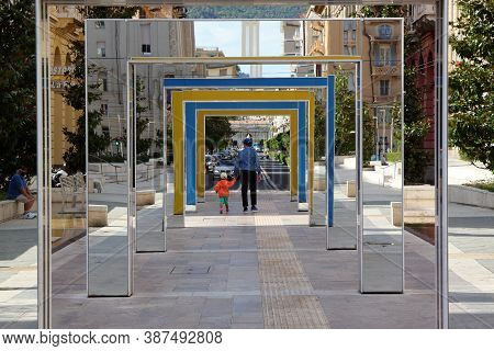 Laspezia, Italy - Summer 2020: A Man And His Child Walk Down A Colorful Hallway In A City Park. High