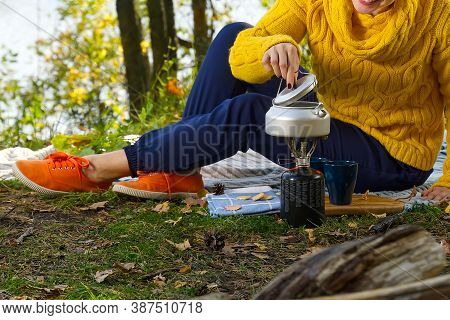Young Beautiful Girl In A Yellow Sweater Makes Coffee In The Forest On A Gas Burner. Making Coffee O