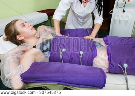 The Beautician Wraps The Woman In A Special Pressotherapy Suit. Losing Weight With Pressotherapy.