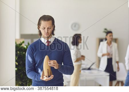 Office Worker Holding Wooden Rocket In Hands In Office
