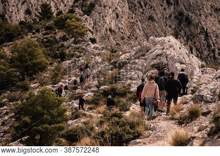 Group Of People Seen From Behind Hiking Above The City Of Omis, Going Towards The Fortica Castle. Co