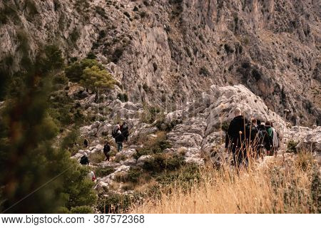 Group Of People Seen From Behind Hiking Above The City Of Omis, Going Towards The Fortica Castle. Co