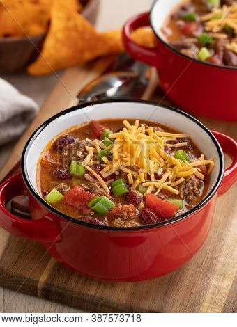 Bowl Of Chili Con Carne With Shredded Ceddar Cheese On A Wooden Board