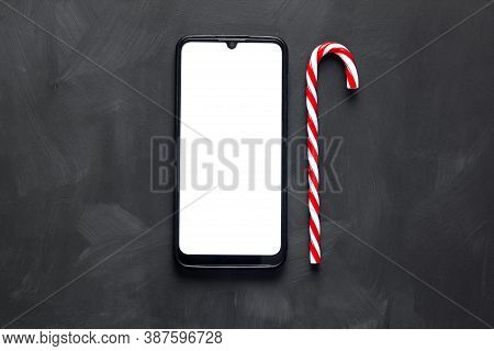 A List Of Christmas Gifts Lies On A Black Table Next To A Decorated Christmas Tree.