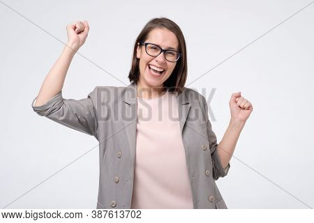 Mature Caucasian Woman In Glasses Doing A Winner Gesture Raising Fists Up
