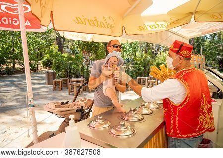 Antalya, Turkey - 4.09.2020: Seller Give Traditional Turkish Ice Cream To Man With Baby Girl In A Su