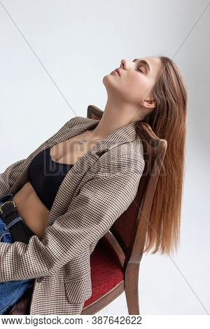 Portrait Of Young Caucasian Woman With Long Hair In Black Top, Blue Jeans And Suit Jacket, Lying On 