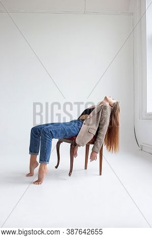 Portrait Of Young Caucasian Woman With Long Hair In Black Top, Blue Jeans And Suit Jacket, Lying On 
