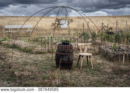 Chair Besides Barrel And Hanging Flower Pot In Permaculture Garden