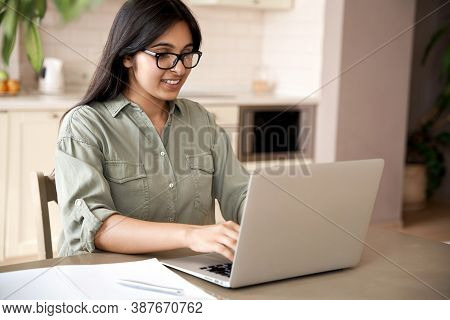 Smiling Indian Young Adult Woman Wearing Glasses Typing On Laptop Computer Working At Home Office Si
