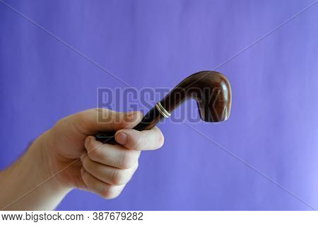 Briar Root Smoking Pipe In Hand. A Mans Hand Holds A Classic Smoking Pipe On A Blue Background. Sele