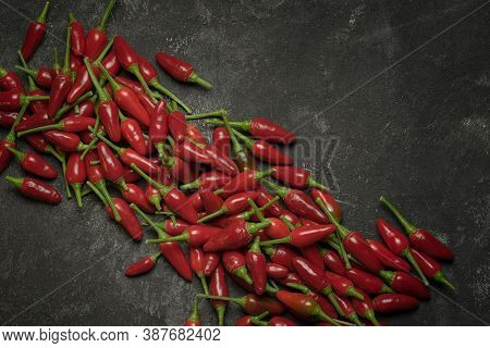 Daigonal Line Of Chilli Peppers On The Black Cement Table.