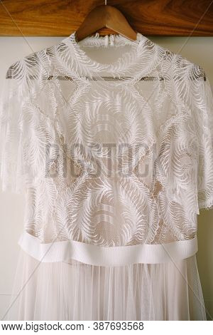 Close-up Of The Top Of A Brides Dress On A Wooden Hanger.