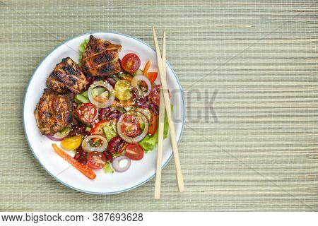 Pan-asian Sesame Salad Plate And Grilled Chicken Pieces In Pad Thai Sauce On A Bamboo Tablecloth And