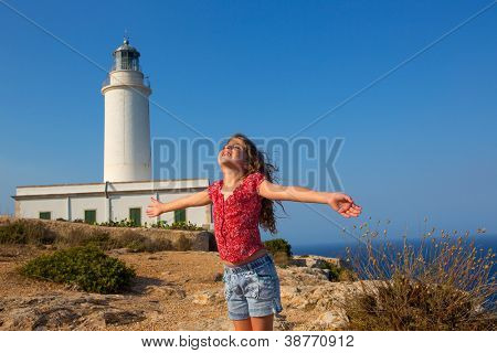 เด็กสาวเปิดมือให้ลมในประภาคารกว้างลาของ Formentera วันสีน้ำเงิน