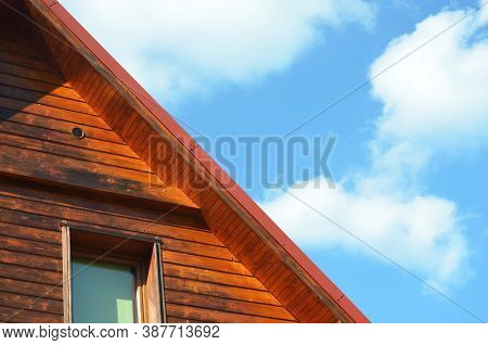 Piece Of Wooden House Facade With Window And Pitched Roof On The Blue Sky Background