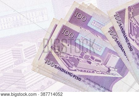 100 Philippine Piso Bills Lies In Stack On Background Of Big Semi-transparent Banknote. Abstract Pre