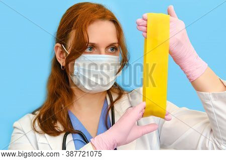 Woman Nurse With Elastic For Sports Stretching On A Blue Background, Face Closeup.