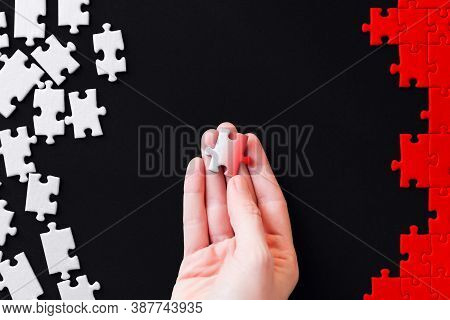Female Hand Is Holding Piece Colored In Gradient. White Puzzles Are Scattered On Left Side And Red S