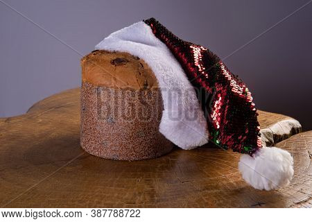 Panettone With Chocolate Chips And Santa Claus Hat On Rustic Wood With Gray Background, Selective Fo