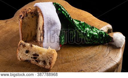 Panettone With Chocolate Chips And Santa Claus Hat On Rustic Wood With Black Background, Selective F