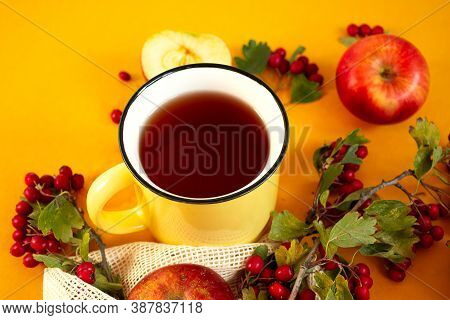 Red Garden Organic Apples, Hawthorn Berries And Cup Of Hot Tea On An Orange Background. Autumn Still