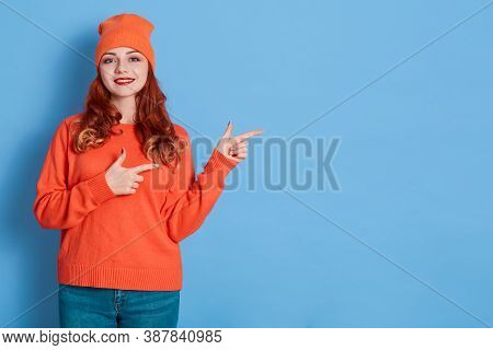 Image Of Young Happy Woman Stands Smiling And Pointing Fingers Aside At Copy Space Isolated Over Blu