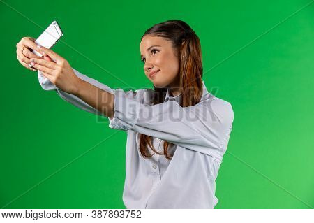 Portrait Of A Smiling Young Caucasian Woman Wearing White Shirt Standing Isolated Over Green Backgro