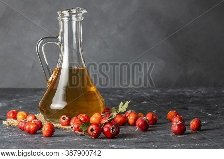 Glass Bottle Of Hawthorn Vinegar With Fresh Ripe Red/yellow Hawthorn Fruits On Rustic Background. Cr