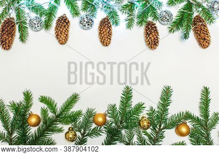 Christmas Composition With Fir Branches And Golden Ornaments Balls On A Blurry Background With Cones