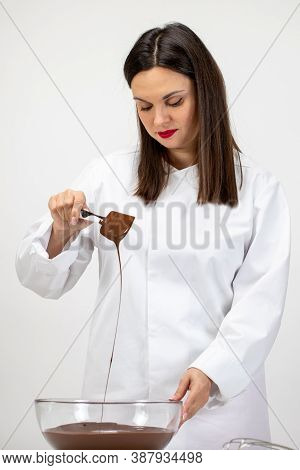 Beautiful Female Pastry-cook Pouring Dark Melted Chocolate Isolated On White Background. Confectione