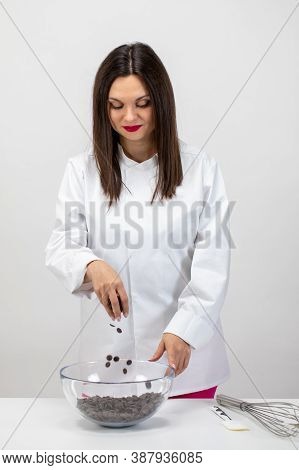 Beautiful Female Confectioner In White Uniform Making Delicious Dessert. Chef Pours Dark Chocolate D
