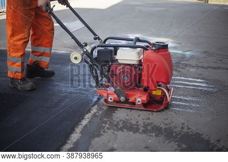 Asphalt Rammer. Laying The Road Surface. Creation Of Parking. The Worker Levels The Road Surface. Ho
