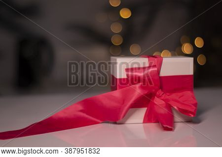 White Gift Box With Pink Ribbon Bow On Gold Bokeh Background