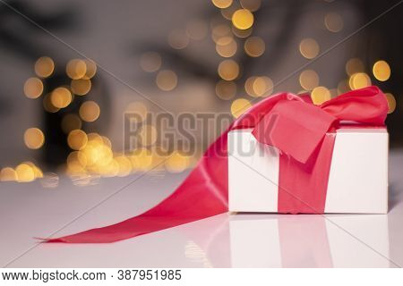 White Gift Box With Pink Ribbon Bow On Gold Bokeh Background