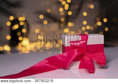 White Gift Box With Pink Ribbon Bow On Gold Bokeh Background