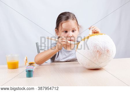 The Child Enthusiastically Makes Crafts For Halloween, Home Pumpkin Decor From Papier Mache, Drawing