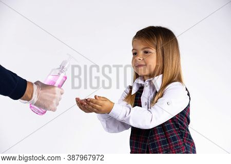Little Girl With School Uniform Disinfecting Hands With Alcohol Sanitizer Gel During Corona Virus An