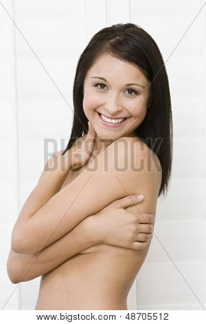 Portret nago uśmiechający się młoda kobieta obejmujące piersi z rękami