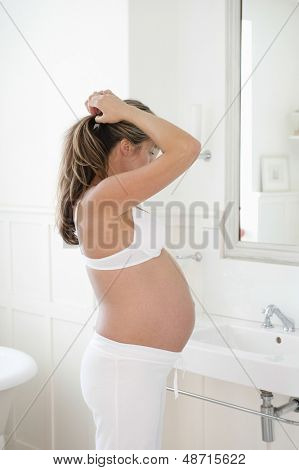 욕실에서 그녀의 머리를 하 고 사이드 뷰 세 젊은 임산부