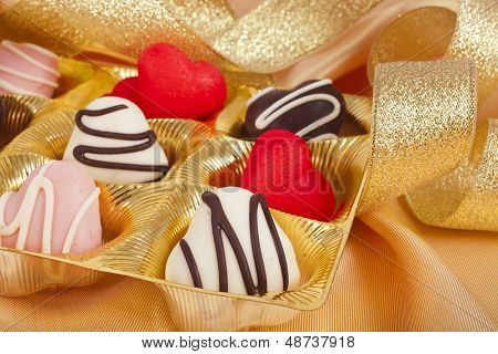 cuori di cioccolato e marchpane caramelle su sfondo dorato stoffa di seta con texture 