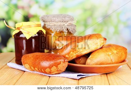 Empanadillas al horno frescos con mermelada de frutas, en la mesa de madera, sobre fondo brillante