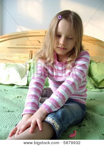 La petite fille assise sur le lit